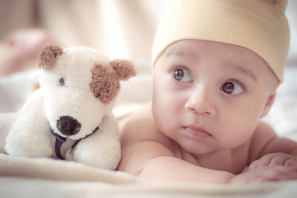 Kleine baby met knuffel | Wanneer geboortekaartjes versturen? Etiquette vraag.